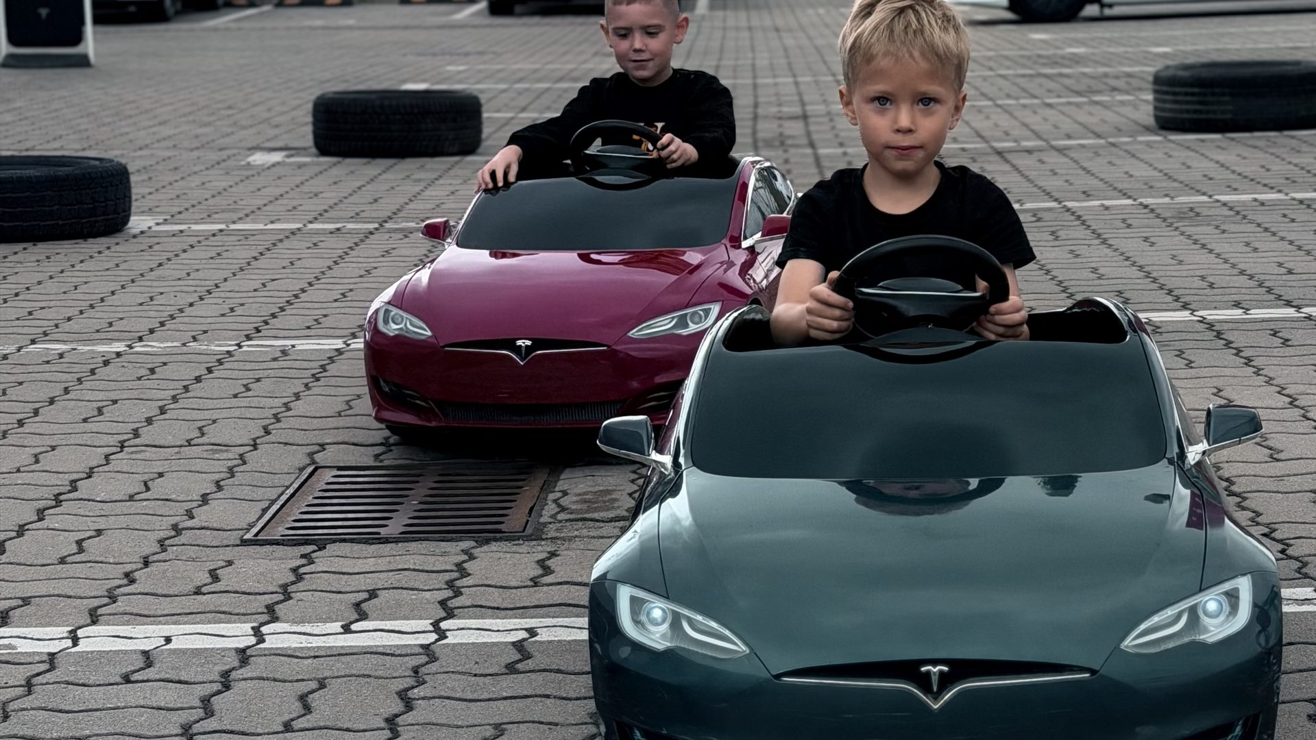 Dzieci w miniaturowych elektrycznych Teslach Model S na torze wyznaczonym oponami przed Tesla Center Warsaw