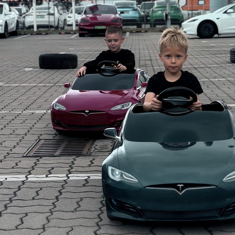 Dzieci w miniaturowych elektrycznych Teslach Model S na torze wyznaczonym oponami przed Tesla Center Warsaw