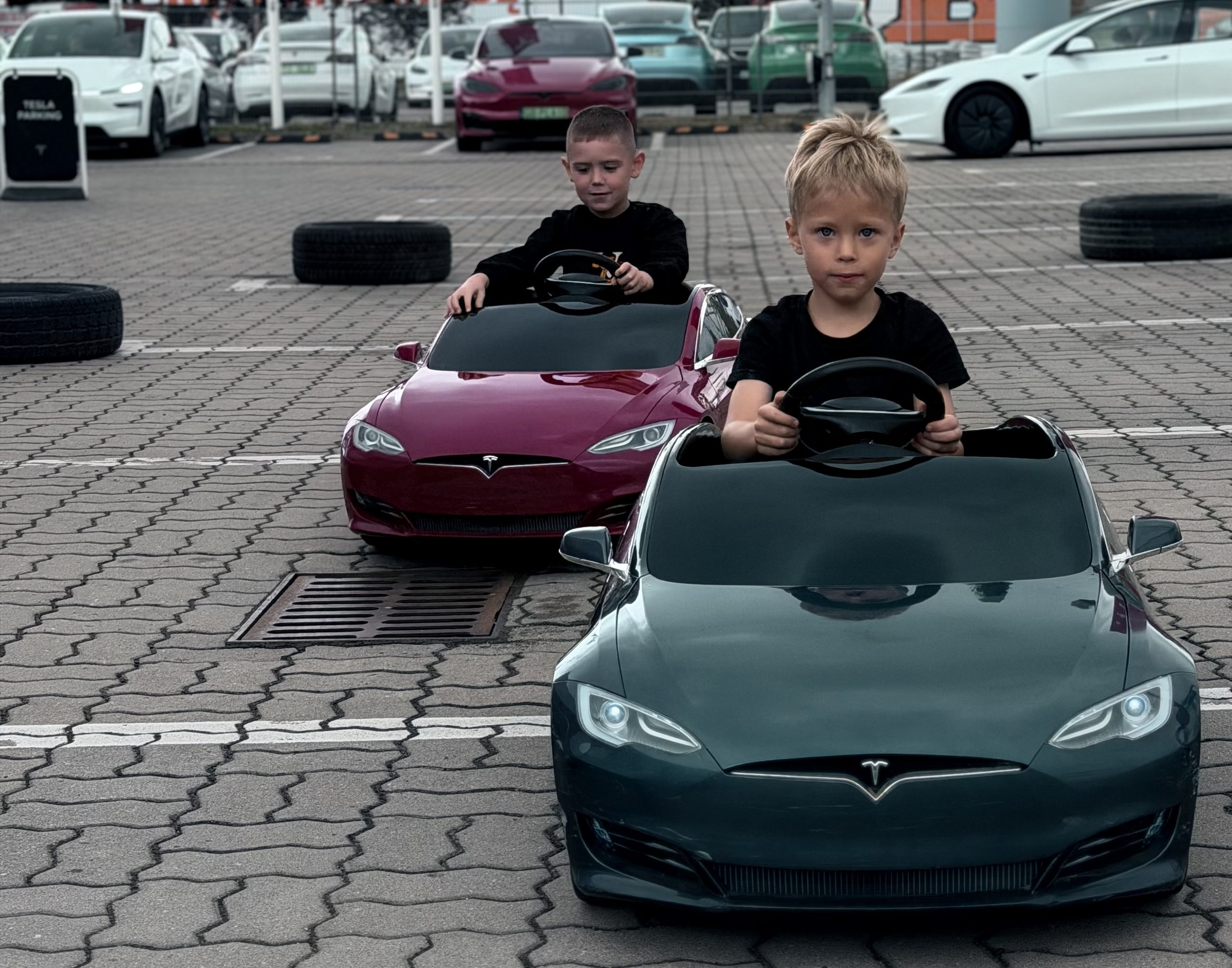 Dzieci w miniaturowych elektrycznych Teslach Model S na torze wyznaczonym oponami przed Tesla Center Warsaw